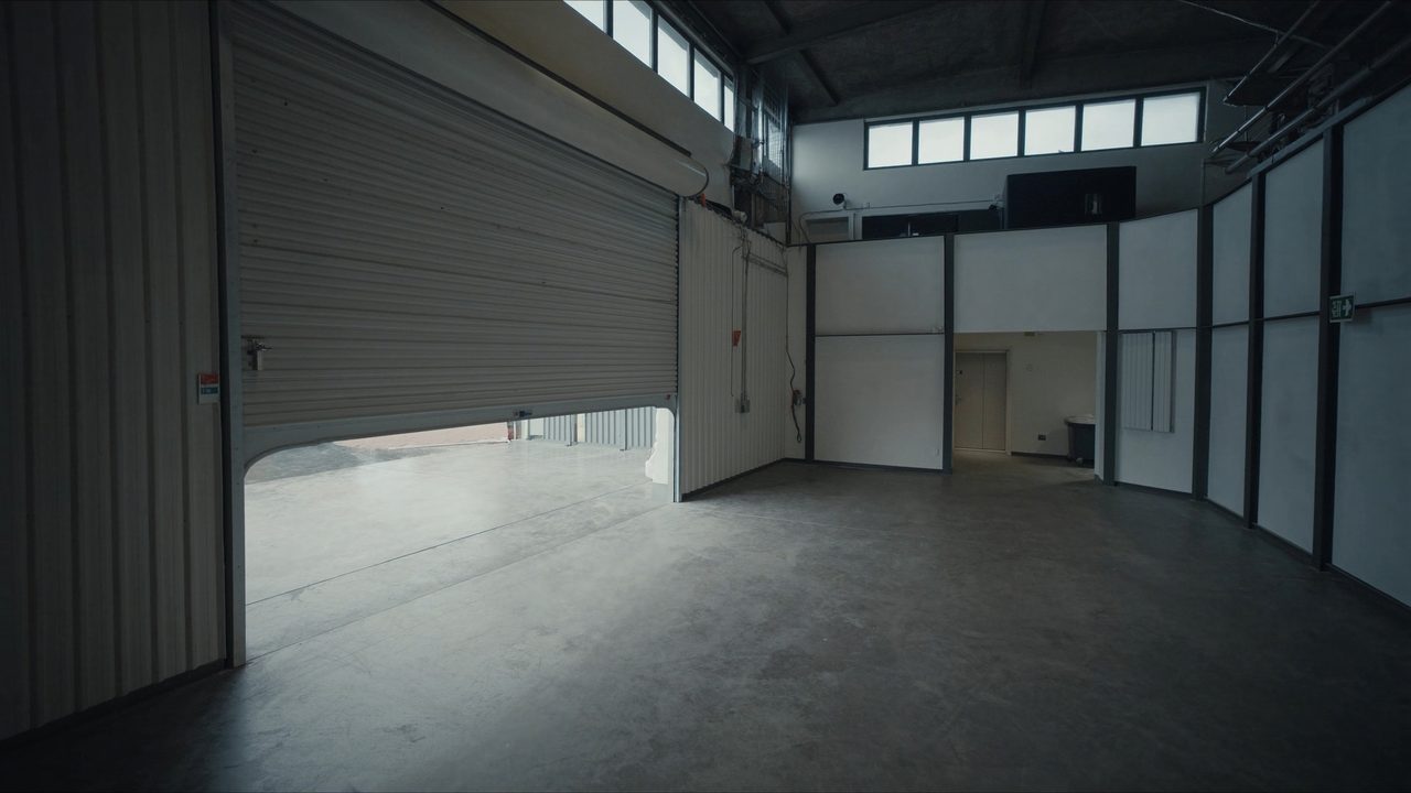 Empty industrial unit interior with roller shutter and high ceiling